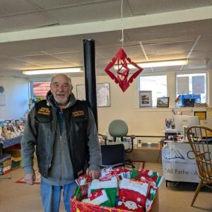 Robert "Biker Bob" Sheehan standing before The Devils Pride Motorcycle Club's donation of Christmas stockings to the Coastal Recovery Community Center located in Rockland. Photo courtesy Bob Sheehan
