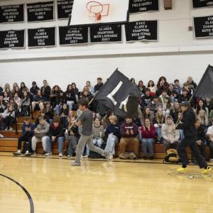 students run through gymnasium carrying flags