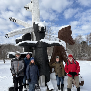 Winter hikers pose in front of a sculpture