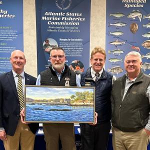 Award winner holds a painting as he and three other men pose for picture