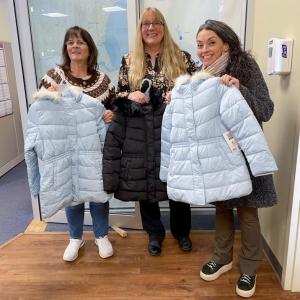 Three women pose with winter coats