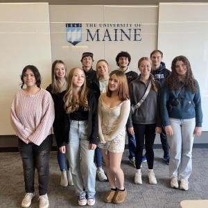 teen group photo in front of a UMaine logo