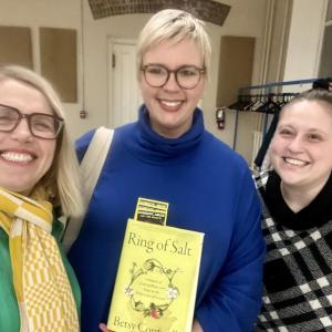 Three women pose with book