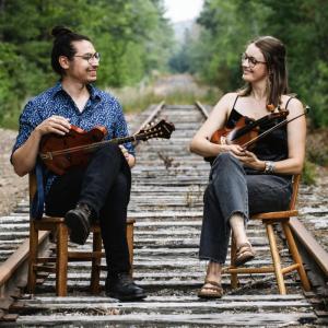 Two musicians seated on train tracks