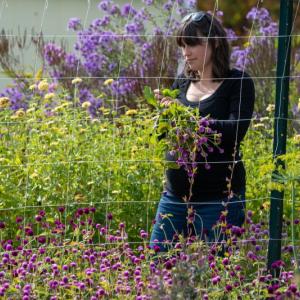 Woman tends to flowers behind a chickenwire fence