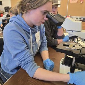 Teen girl looks into microscope