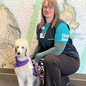 woman kneels next to white dog