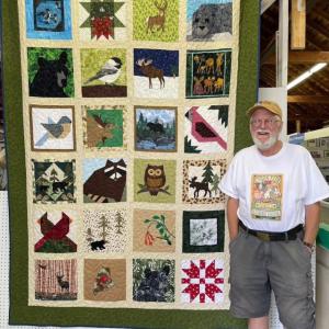 man poses with quilt