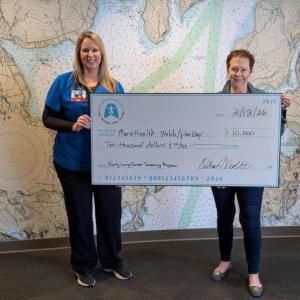 Two women hold an oversized check