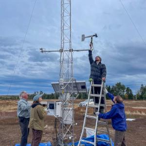 Four people work around tower