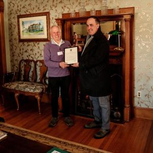 Two men hold framed proclamation