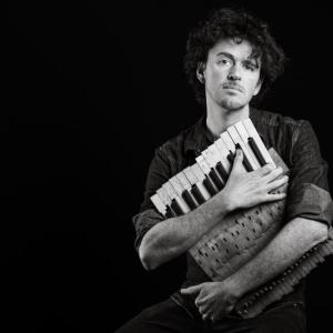 person holding instrument in front of black background