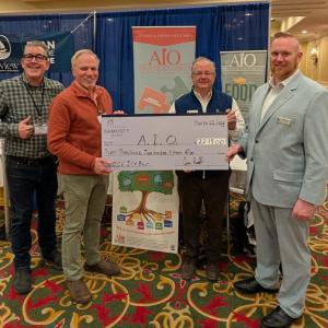 four men pose with oversize check 