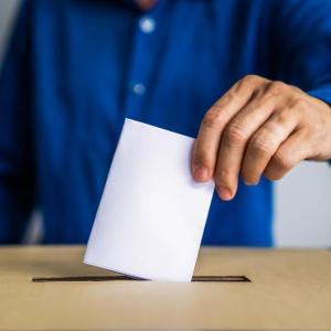 a man inserts his ballot into a box