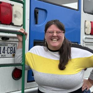 woman outside rear of bus