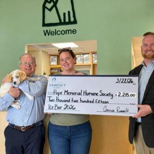 Three adults and a dog pose with oversize check