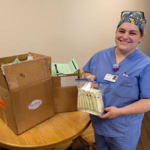 woman in scrubs poses with donation kit