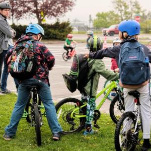 three backpack-wearing kids on bikes