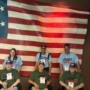 three sets of participants in front of flag