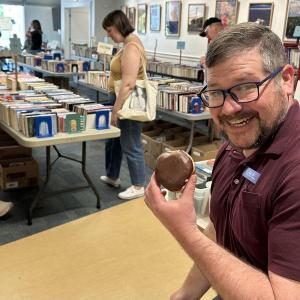 man holding doughnut at book sale
