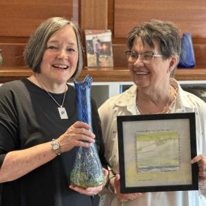 two women pose with examples of their art