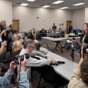 journalists crowd around an election official 