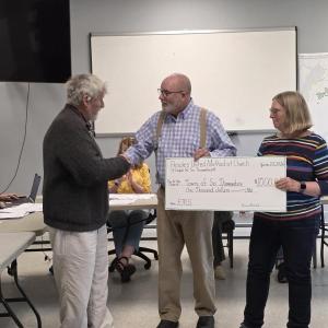 three adults stand with presentation check