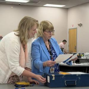 election officials look at pieces of paper.