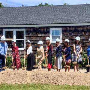 multiple people hold shovels ladened with dirt