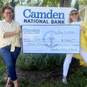 two women pose with presentation check