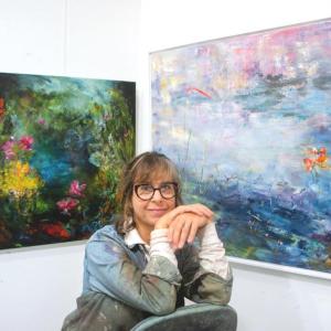 woman poses in front of paintings