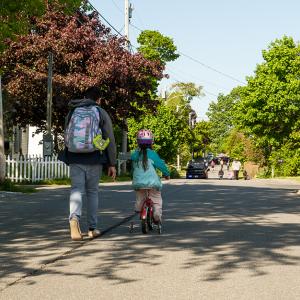 children wearing backpacks ride bikes