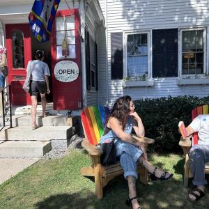 shopper enters store while two others sit in Adirondack chairs