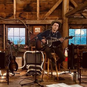 male playing guitar in barn