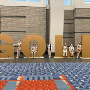 girls sit on "Gold" statue