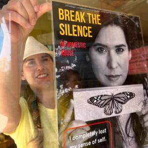 woman hangs a poster in a window