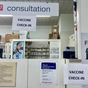 vaccine check-in signs at a pharmacy counter