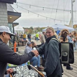 Mast Landing's Gabe Vickery hands Kathryn Rogers from Owls Head a beer as she, and her backpack buddy, Ziggy, enjoy the festival. Photo by Kay Stephens