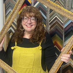 woman poses through empty picture frame