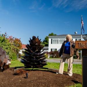 woman, lectern, two pine cone sculptures