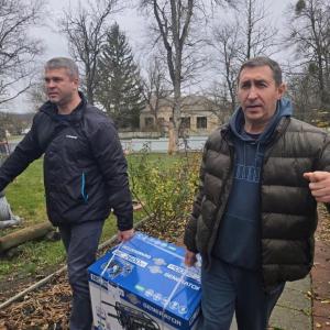 two adults carry a generator