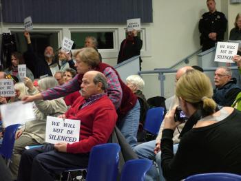 Opponents of the proposed propane terminal hold up signs in protest of the Searsport Planning Board's decision to end public comment with a dozen citizens waiting in line to speak. (Photo by Ethan Andrews)