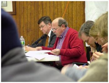David Italiaander, center in red, testifies against the tank Wednesday night. Italiaander is flanked by attorneys Ed Bearor, left, and Steve Hinchman, right. (Photo by Ethan Andrews)