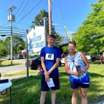 Two people before the race in front of the Thomaston Public Library sign.
