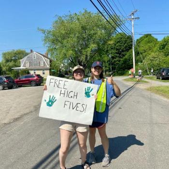 Two people cheer on racers with a sign that says Free High Fives”