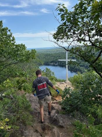 The cross at the top of Maiden's Cliff in Camden Hills State Park, where hikers carefully avoid the edge of the rocks while viewing a landscape that overlooks the lake. (Photo courtesy Bennett Cohen) c