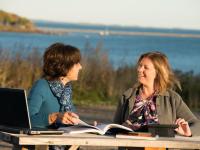 UMA Rockland Center Two students studying with the Rockland Breakwater in the background